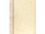 an old book sitting on top of a white table next to a white wall