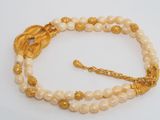 a close up of a bracelet with pearls and gold