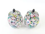 pair of colorful floral covered jars on a white surface