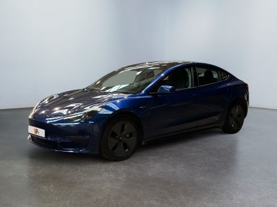 une Tesla Model 3 bleue garée dans une pièce blanche