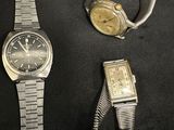 two watches and a bracelet on a black surface
