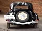 a black car parked in front of a brick wall