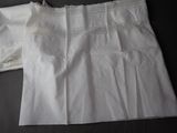 two pieces of white clothing that are laying on a bed