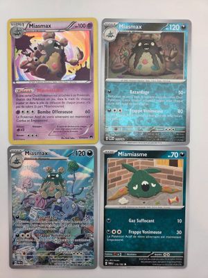 Quatre cartes Pokémon différentes sont posées sur une table avec un fond blanc.