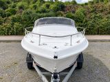 a white boat parked on a trailer in a parking lot