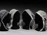 trois têtes de mannequin recouvertes de voiles blancs et une tête de mannequin noire recouverte d'un voile blanc