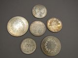 six different types of silver coins on a black surface