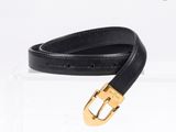 ceinture en cuir noir avec boucle dorée, présentée dans un coffret en acrylique transparent
