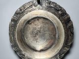 an old silver plate with a handle on a white surface