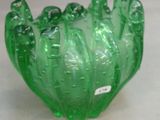 a green glass bowl sitting on a table next to a wall