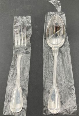 two forks and spoons wrapped in plastic on a table