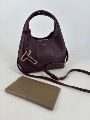 the brown purse is next to a brown wallet on a white surface
