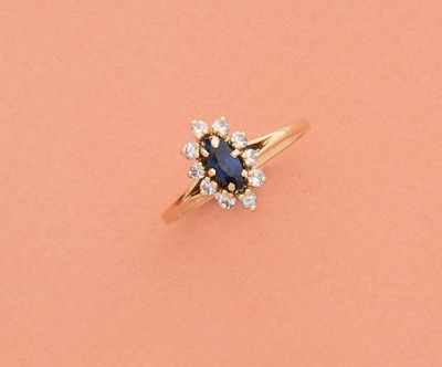 une bague sertie d'un saphir bleu et de diamants sur fond rose