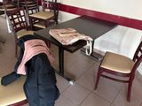une table et des chaises dans un restaurant, avec un sac à dos posé par terre