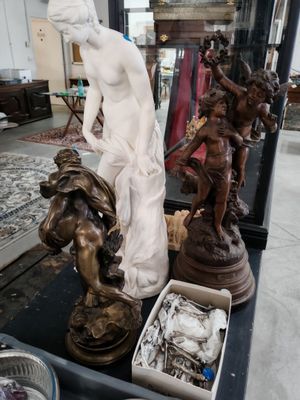 une statue représentant une femme assise sur une table, à côté d'autres statues