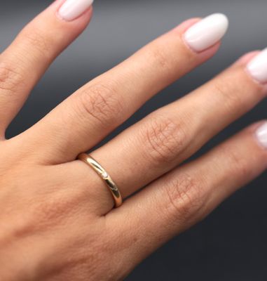 the woman ' s hand is holding a gold ring with a diamond on it