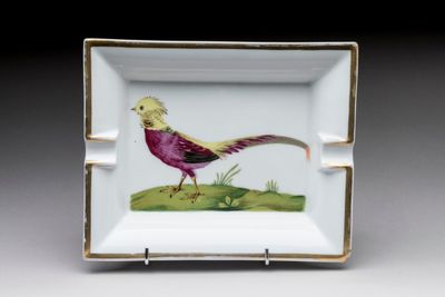 a small square plate with a bird painted on it