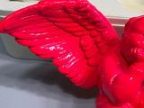 a red angel figurine sitting on a table next to a white box