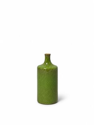 the small green bottle is sitting on a white surface