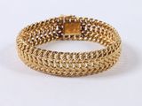 a close up of a gold bracelet on a white surface