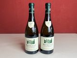 Deux bouteilles de vin sont posées sur un comptoir devant un mur rouge.