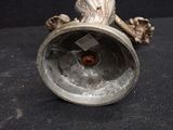 a silver vase with a bird on it on a black surface