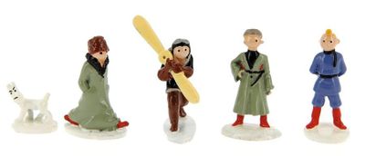 four figurines of people and a dog on a white surface