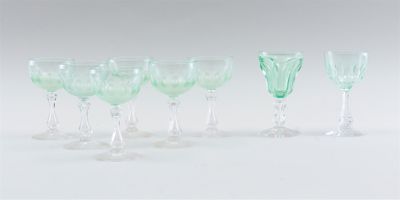 several green wine glasses are lined up on a white surface