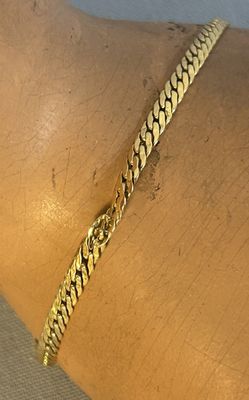 quelqu'un porte au poignet un bracelet en or muni d'une chaîne
