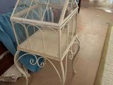 a small white bird cage sitting on top of a bed