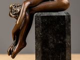 bronze sculpture of a woman laying down on a black marble block