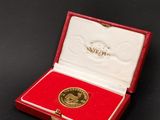 un gros plan sur une petite boîte rouge contenant une médaille d'or
