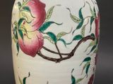 a white vase with pink flowers and green leaves on it