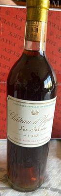 une bouteille de vin posée sur une table, avec une boîte rouge en arrière-plan