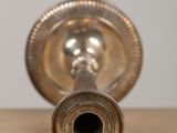a silver candle holder on a table with a white wall in the background