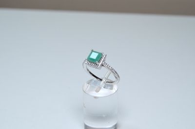 a ring with a green stone on it sitting on a clear glass