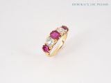a close up of a ring with three stones on a white surface
