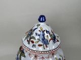 a white vase with a blue lid and a flower design on it