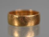 un gros plan d'une alliance en or posée sur une surface réfléchissante