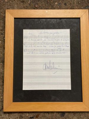 a framed photograph of a piece of music paper with a handwritten note