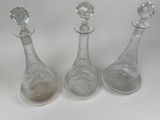 three clear glass decanters sitting next to each other on a white surface