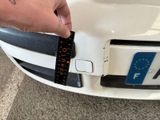 a person that is holding a piece of tape on the front of a car