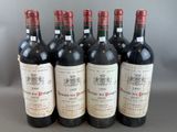 six bottles of red wine are lined up on a table