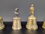 quatre clochettes en laiton antique sont alignées sur une surface noire