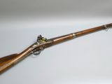 un fusil au canon en bois et aux garnitures en laiton, sur fond blanc
