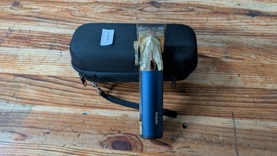 une valise noire avec une poignée bleue posée sur un parquet