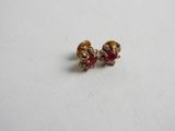 a pair of gold and ruby earrings on a white surface