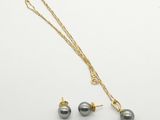 a necklace and earring set with grey pearls on a white background