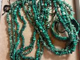 several pieces of green necklaces and bracelets in a box