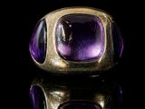 a close up of a gold ring with a purple stone